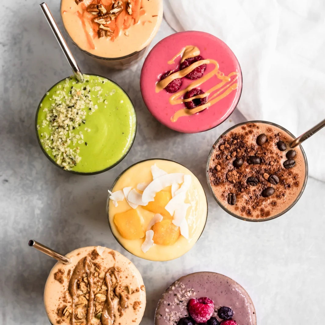 7 colourful smoothies arranged on marble
